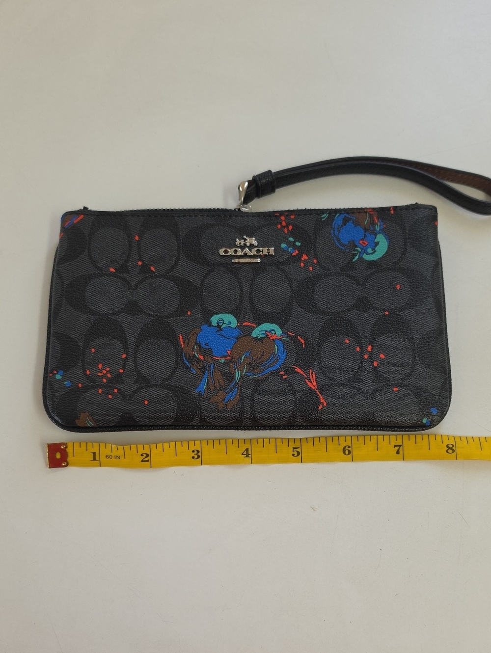 This Coach black wristlet features a limited edition bird motif on coated canvas
